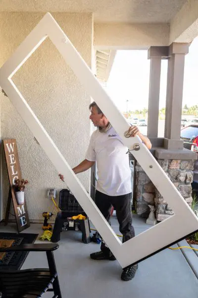 A man holding up a door frame in the middle of a room.
